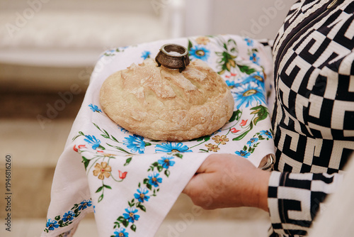 фотографія Woman holding traditional Slavic wedding bread Karavai with a salt cellar on an embroidered floral towel
