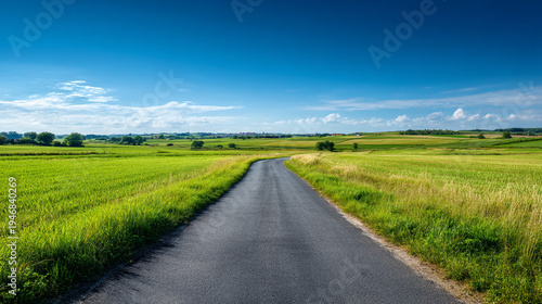 A long straight road leads through a green countryside landscape