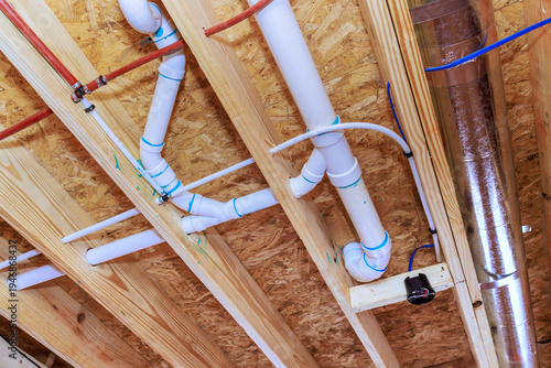 Pipes ducts installed under wooden ceiling in construction site for building project