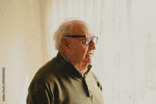 Foto Elderly man with glasses looking through window