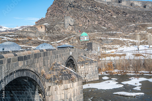The scenic view of Kars, the Kars River, and the historical stone bridge in winter on a snowy day, in Turkey. 