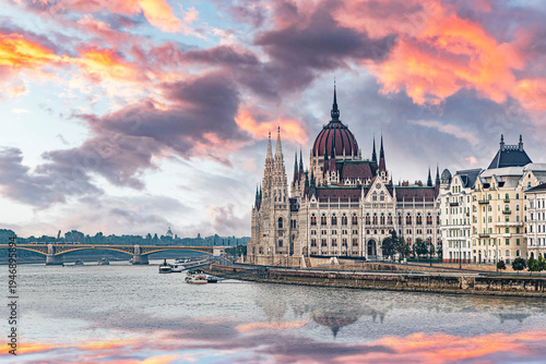 The Hungarian Parliament Building in Budapest situated along the banks of the Danube River under a vibrant sunset sky.