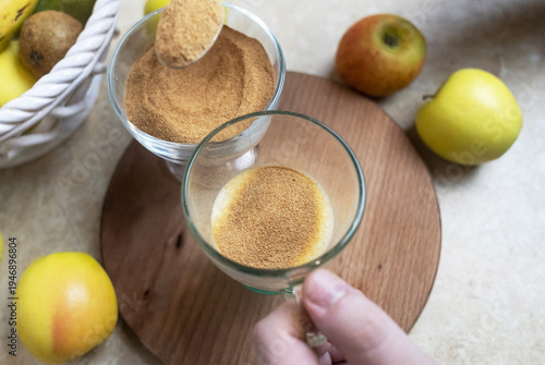 Wallpaper Mural Person adding apple fiber powder to a glass of yogurt, surrounded by fresh apples and walnuts. Healthy prebiotic supplement for gut health, digestion and weight management. Torontodigital.ca