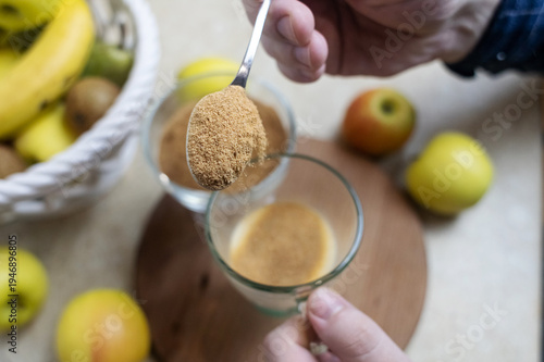 Wallpaper Mural Person adding apple fiber powder to a glass of yogurt, surrounded by fresh apples and walnuts. Healthy prebiotic supplement for gut health, digestion and weight management. Torontodigital.ca