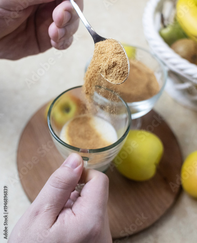 Wallpaper Mural Person adding apple fiber powder to a glass of yogurt, surrounded by fresh apples and walnuts. Healthy prebiotic supplement for gut health, digestion and weight management. Torontodigital.ca