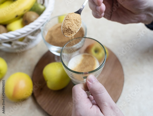 Wallpaper Mural Person adding apple fiber powder to a glass of yogurt, surrounded by fresh apples and walnuts. Healthy prebiotic supplement for gut health, digestion and weight management. Torontodigital.ca