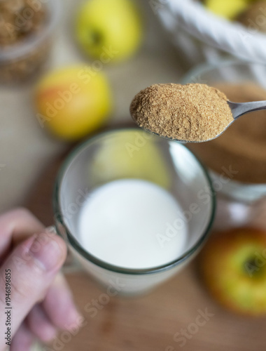 Wallpaper Mural Person adding apple fiber powder to a glass of yogurt, surrounded by fresh apples and walnuts. Healthy prebiotic supplement for gut health, digestion and weight management. Torontodigital.ca