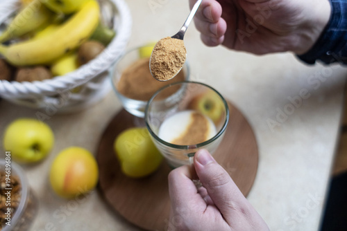 Wallpaper Mural Person adding apple fiber powder to a glass of yogurt, surrounded by fresh apples and walnuts. Healthy prebiotic supplement for gut health, digestion and weight management. Torontodigital.ca