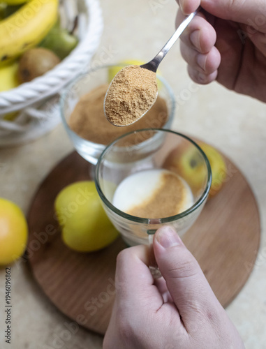 Wallpaper Mural Person adding apple fiber powder to a glass of yogurt, surrounded by fresh apples and walnuts. Healthy prebiotic supplement for gut health, digestion and weight management. Torontodigital.ca