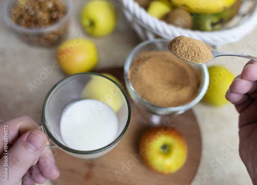 Wallpaper Mural Person adding apple fiber powder to a glass of yogurt, surrounded by fresh apples and walnuts. Healthy prebiotic supplement for gut health, digestion and weight management. Torontodigital.ca