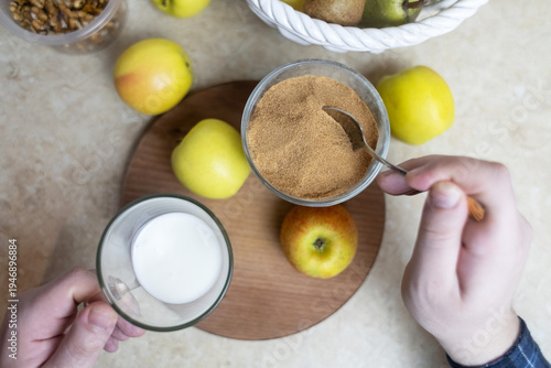 Wallpaper Mural Person adding apple fiber powder to a glass of yogurt, surrounded by fresh apples and walnuts. Healthy prebiotic supplement for gut health, digestion and weight management. Torontodigital.ca