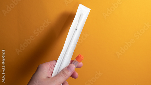 фотографія Hand holding home DNA testing kit with saliva sample tube for genetic ancestry t