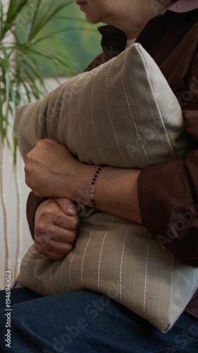 Vertical midsection shot of unrecognizable female patient hugging pillow tightly against chest to cope with anxiety attending psychologist office