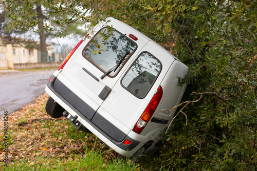 Voiture blanche utilitaire commercial tombée dans le fossé après un accident en dérapage dans un virage d'une petite route départementale.