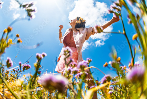 Happy woman enjoying nature outdoors among flowers. Outdoors.