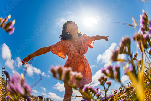 Summer mood. young and cheerful girl in summer dress posing against blue sky and flowers. beautiful girl dancing among flowers. girl enjoying summer.