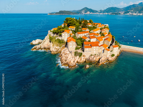 Aerial view of Sveti Stefan's terracotta rooftops nestled on a rocky islet against the azure Adriatic, a jewel of the Montenegrin coast, Sveti Stefan, Budva Municipality, Montenegro.