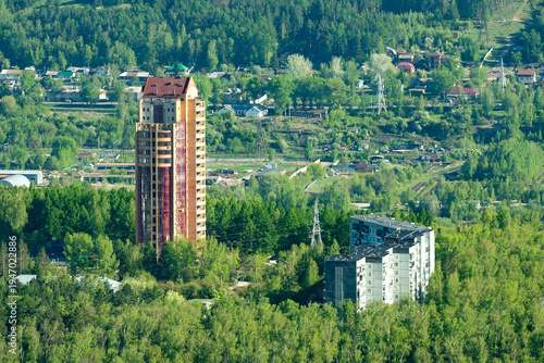 High-Rise Apartment Tower Surrounded by Lush Forest and Suburban Houses in Spring