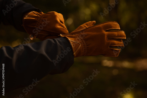 Fotografía Close-up of a person putting on premium brown leather work gloves outdoors during golden hour