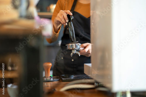 Barista tamping coffee in portafilter at cafe