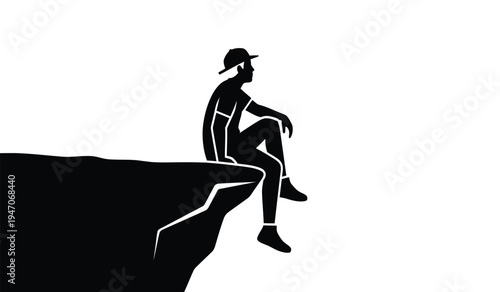 A silhouette of a boy wearing a baseball cap sitting alone on the edge of a high cliff looking out