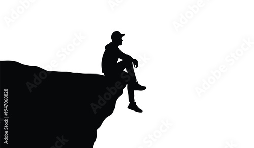 A silhouette of a lone person wearing a cap sitting on the edge of a high cliff looking forward