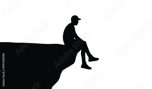 A silhouette of a person wearing a cap sitting on the edge of a high cliff looking into distance