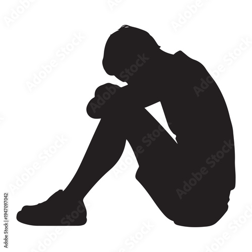 A solitary figure sits with knees drawn up appearing lost in thought a dark silhouette