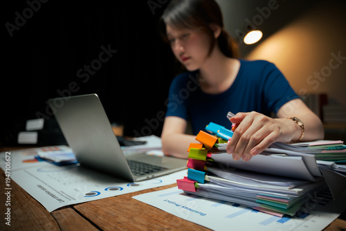 Young woman working late managing many business documents