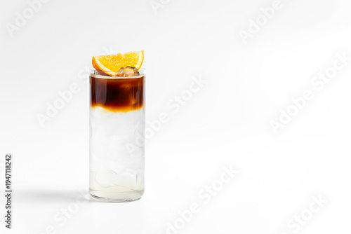 Refreshing iced cold classic espresso coffee tonic in a highball glass with an orange wedge garnish for a hot summer day on white background with copy space