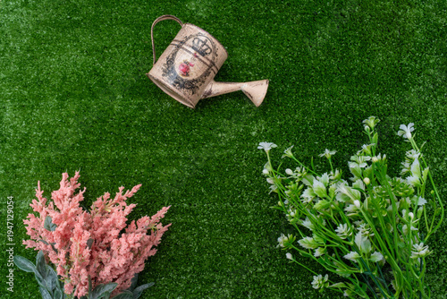 Spring gardening flat lay with vintage watering can and flowers on green grass.
