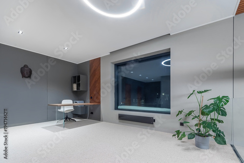 A spacious high-tech room decorated in white and gray. Panoramic window, modern furniture.