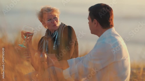 Romantic mature couple drinking wine at sunset