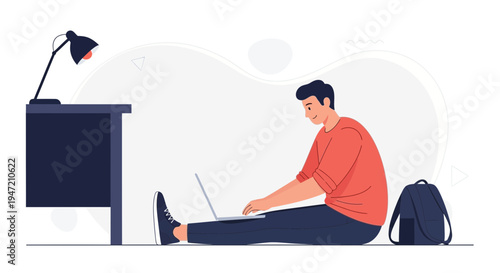 Young man working on laptop on floor, desk and lamp nearby, backpack