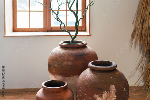 Wallpaper Mural Rustic interior with handmade large clay pottery vases and dry branches standing on floor near window. Interior boho or wabi-sabi with natural materials. Terracotta ceramic jars in a neutral space Torontodigital.ca