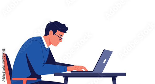 Young man wearing glasses and a blue sweater focused on typing on a laptop computer while sitting at a dark desk.