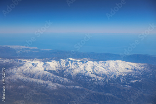 Sierra nevada mountains aerial view with mediterranean sea. Snow capped sierra nevada mountains extending to the mediterranean sea and clear blue sky