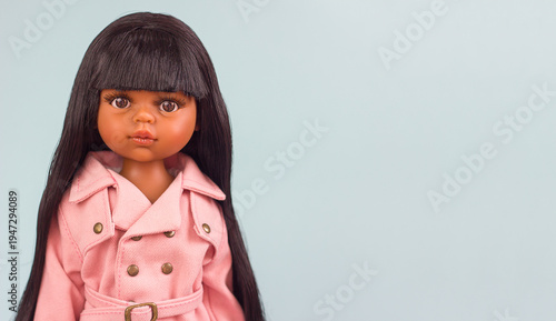Beautiful vinyl mulatto doll in fashionable and stylish clothes, modern dolls for modern children, selective focus
