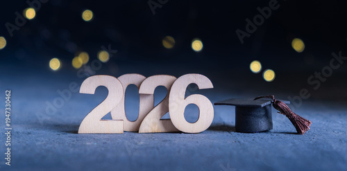 Class of 2026 banner. Number 2026 with graduate hat on dark blue background with bokeh