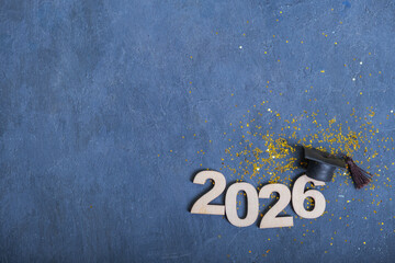 Number 2026 with graduation cap on dark blue background with tinsel