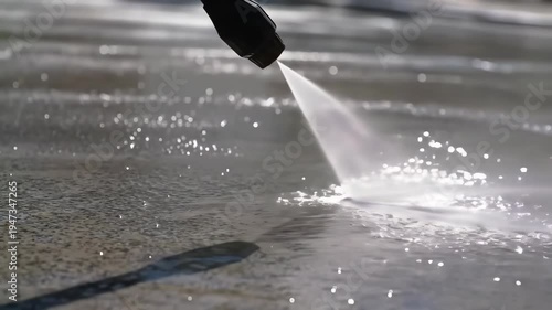High-Pressure Water Jet Cleaning Dirty Pavement Surface with Splashing Water Droplets.