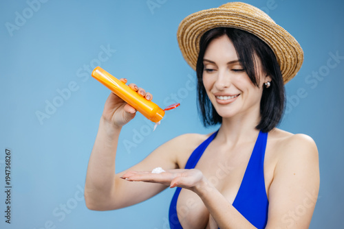 Photos Female model in a swimsuit applying sunscreen cream on her skin isolated on a clean background