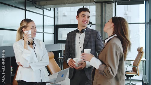 Discussion among coworkers in an office space during afternoon hours with drinks in hand