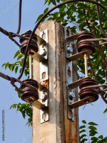 Close-up of electrical pole with tangled wires and insulators in the city.