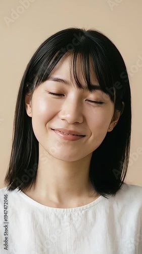 Serene young Asian woman smiling peacefully with eyes closed