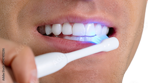 close up woman brushing teeth with electric toothbrush glowing blue light dental hygiene oral care concept isolated 