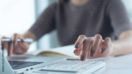 Close up woman using calculator to calculate home finance and writing note, accounting on table, budget management. budgeting and tax calculation