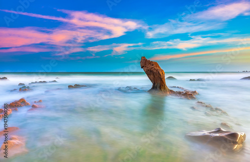 Wallpaper Mural Coastal landscape at sunset featuring colorful skies reflected on the calm ocean water. Unique rock formations rise from the shallow sea while waves gently flow around the rocky shoreline.  Torontodigital.ca