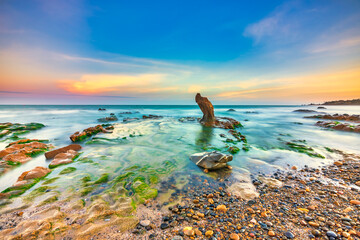 Plexiglas schilderij Reflectie Kustlandschap met rotsformaties bij zonsondergang  © huythoai