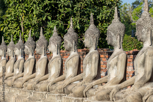 Row of statues at phra chedi chaimonkhon, in Ayutthaya, Thailand, the ancient capital of Siam. A Unesco Heritage Site. Brick chedis in the background.
